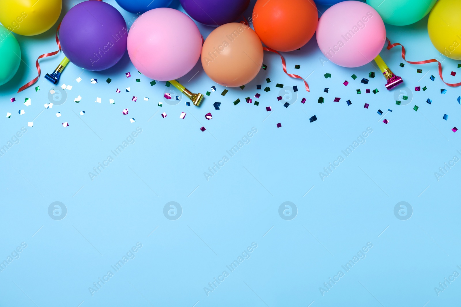 Photo of Flat lay composition with balloons and confetti on light blue background, space for text. Birthday decor