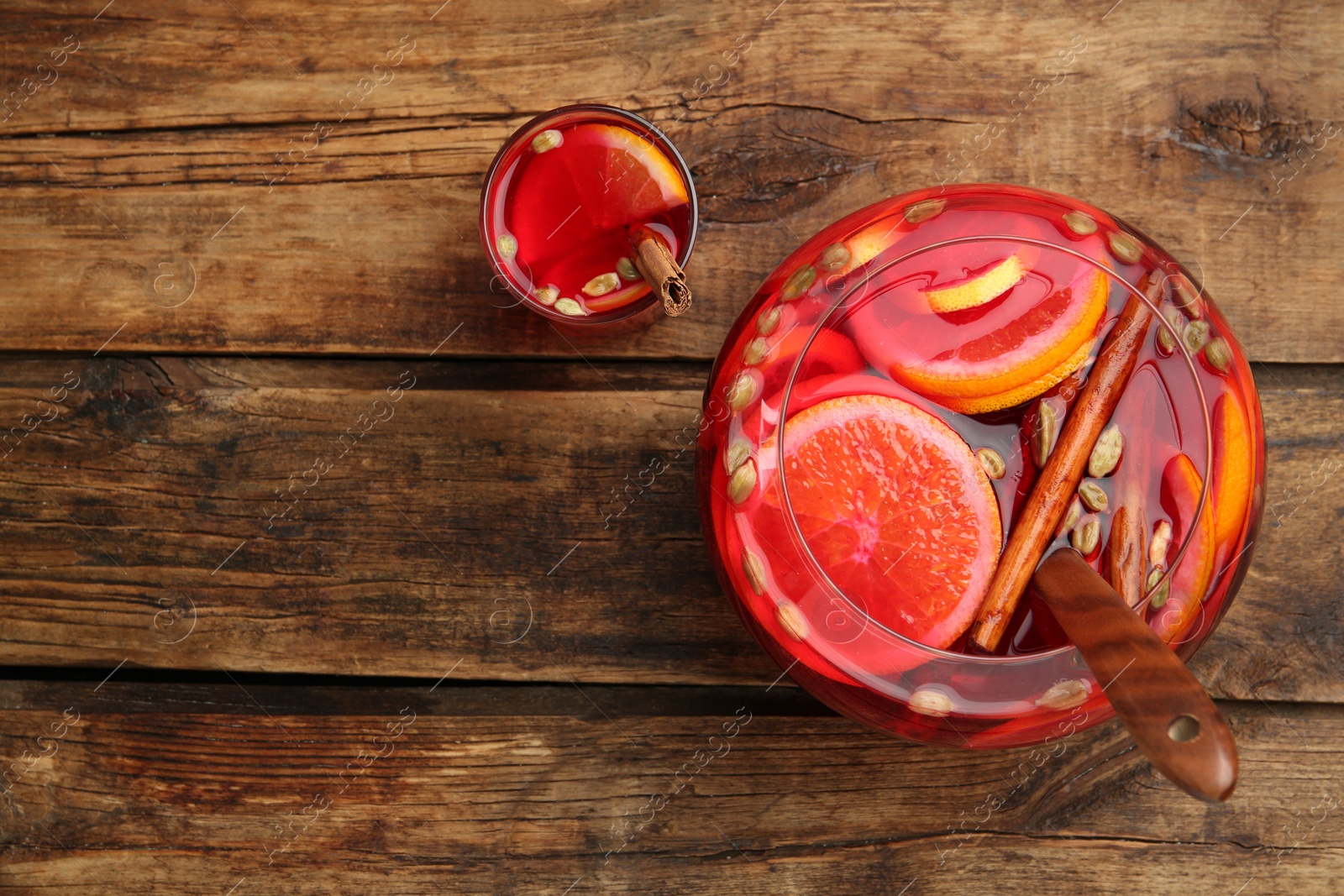 Photo of Glass and bowl with aromatic punch drink on wooden table, flat lay. Space for text