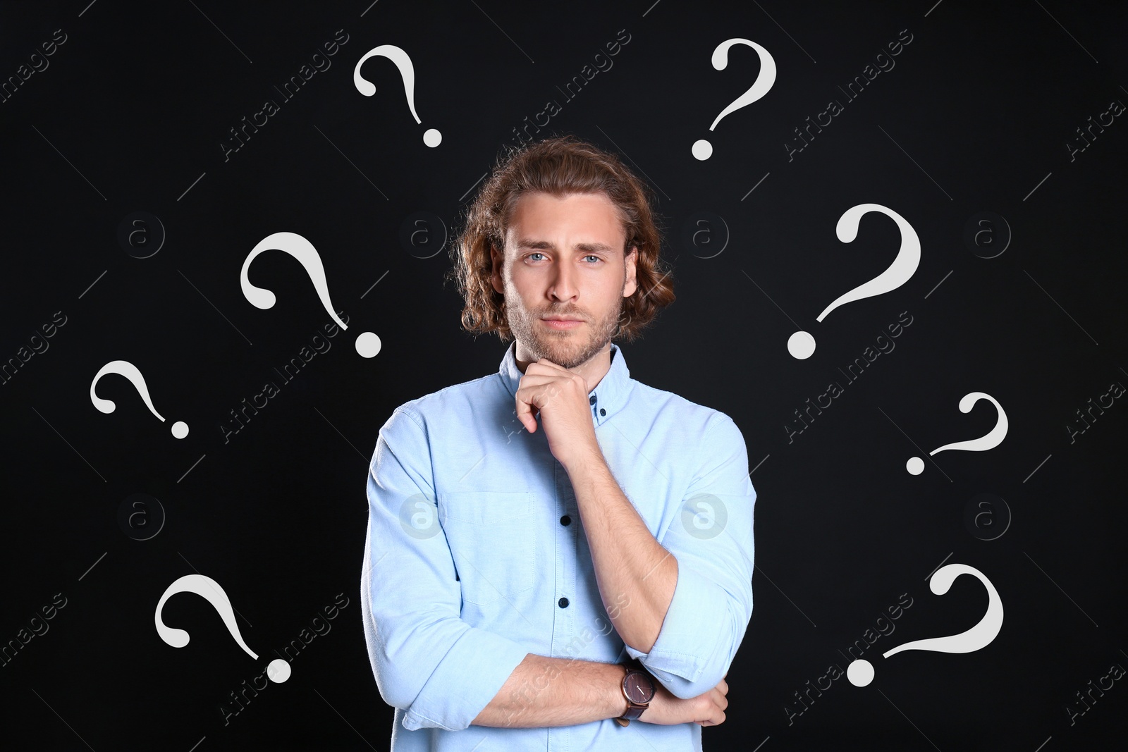 Image of Choice in profession or other areas of life, concept. Making decision, thoughtful young man surrounded by drawn question marks on black background