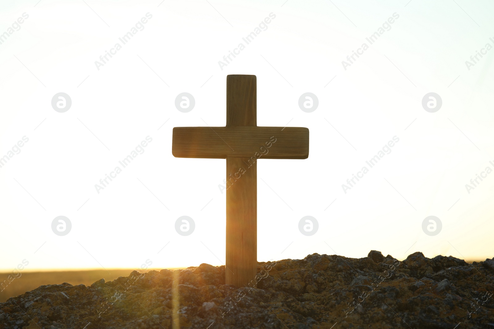 Photo of Wooden Christian cross outdoors at sunrise. Religion concept