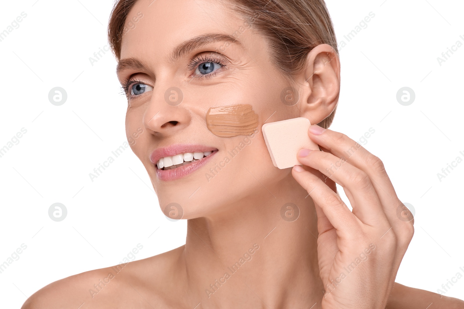 Photo of Woman applying foundation on face with makeup sponge against white background