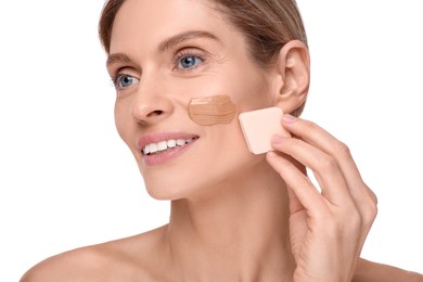 Woman applying foundation on face with makeup sponge against white background