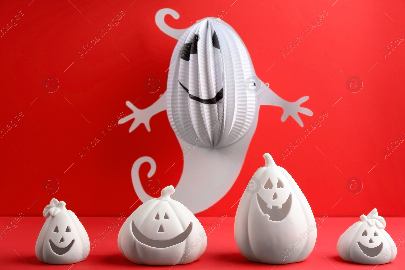 Photo of Composition with pumpkin shaped candle holders on red background. Halloween decoration