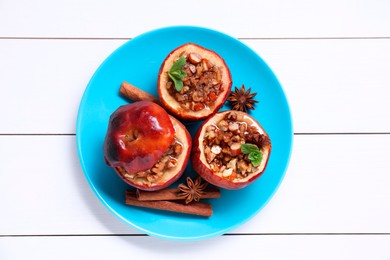 Tasty baked apples with nuts, honey, spices and mint on white wooden table, top view