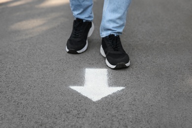 Photo of Man standing near arrow on asphalt, closeup