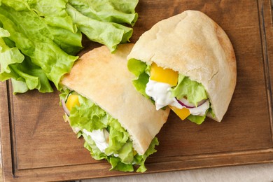 Photo of Delicious pita sandwiches with chicken breast and vegetables on wooden table, flat lay
