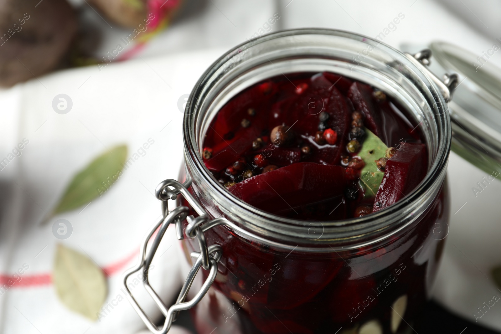 Photo of Pickled beets in glass preserving jar on table, closeup