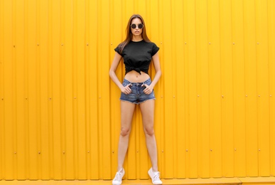 Photo of Young woman wearing black t-shirt near color wall on street