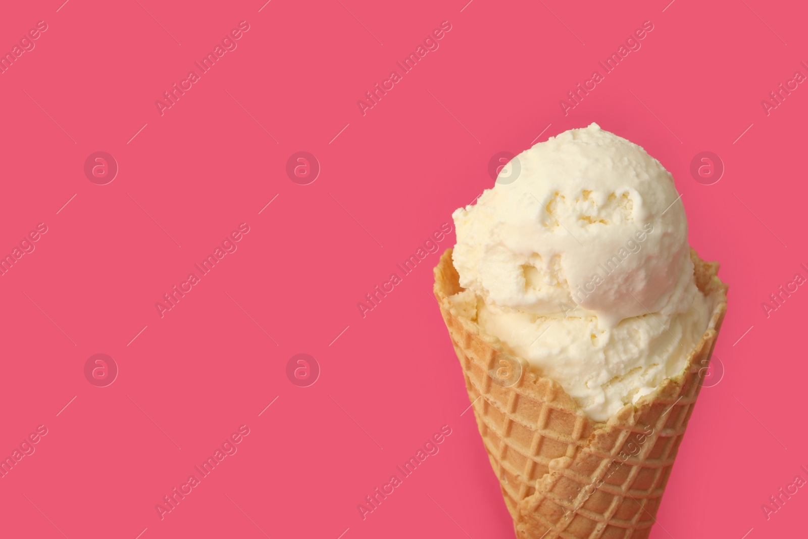 Photo of Delicious ice cream in waffle cone on pink background, closeup. Space for text