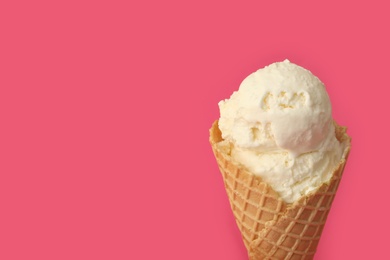 Photo of Delicious ice cream in waffle cone on pink background, closeup. Space for text