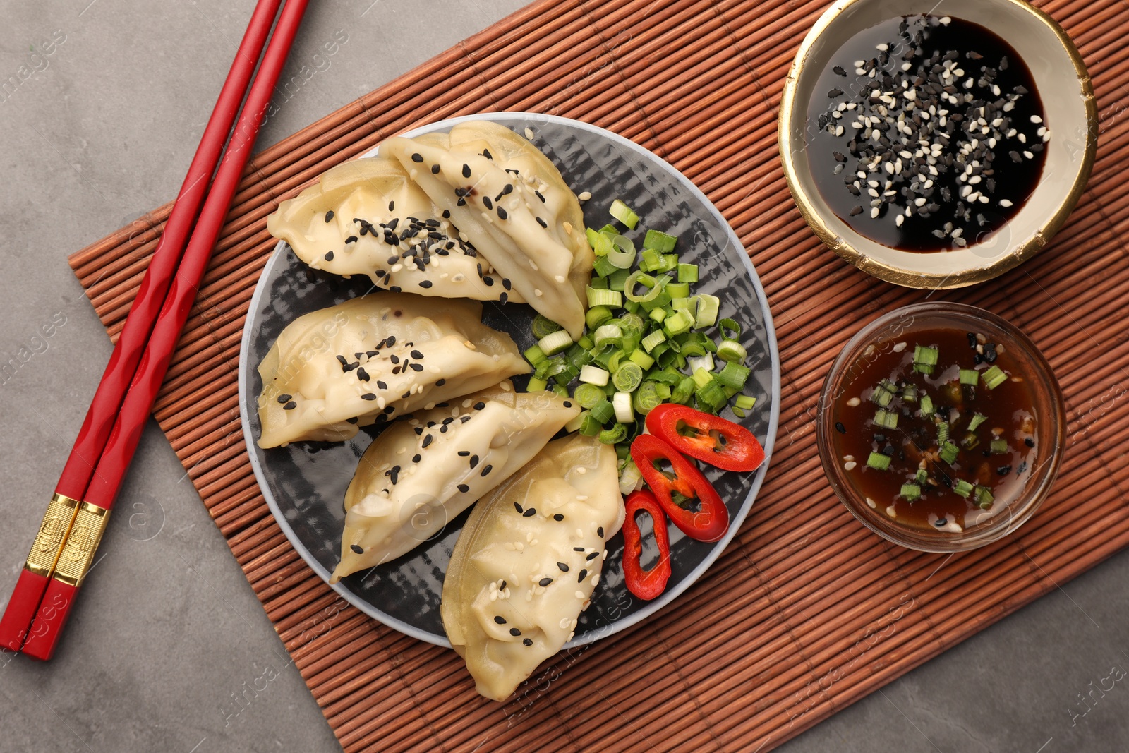 Photo of Delicious gyoza (asian dumplings) served on gray table, flat lay