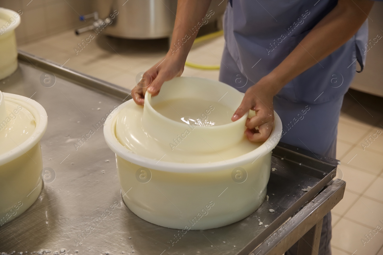 Photo of Worker taking fresh cheese from mould at modern factory, closeup