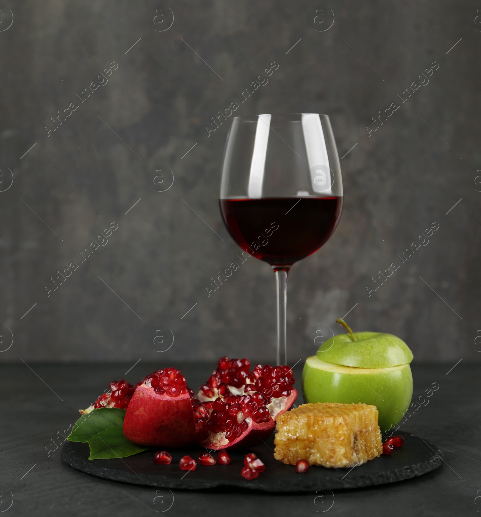 Photo of Honeycomb, fruits and wine on grey table, space for text. Rosh Hashanah holiday