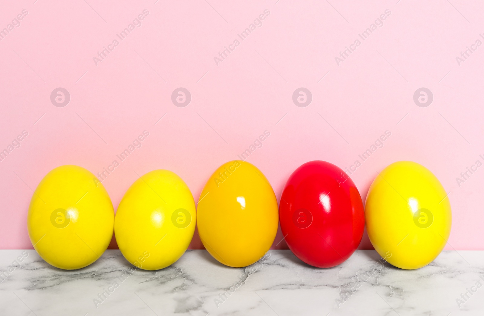 Photo of Easter eggs on white marble table against pink background, space for text