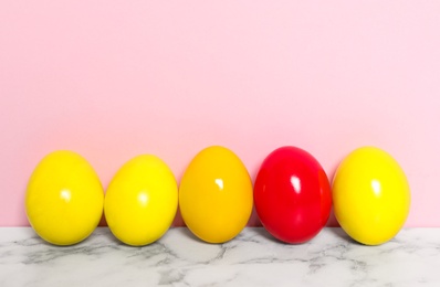 Easter eggs on white marble table against pink background, space for text