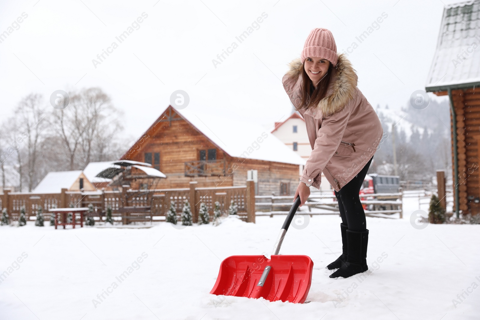 Photo of Young woman cleaning snow with shovel near her house. Space for text