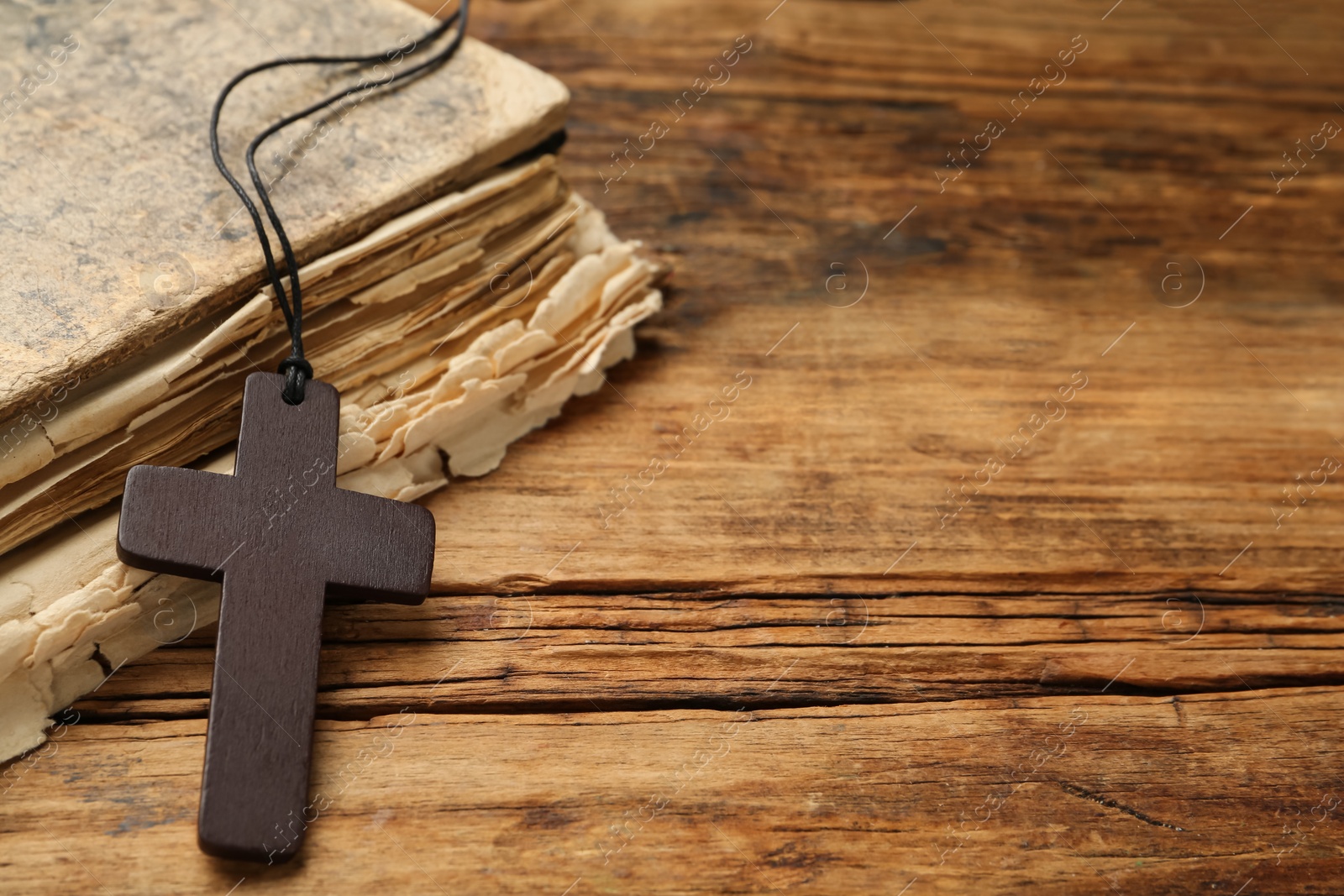 Photo of Christian cross and Bible on wooden table, space for text