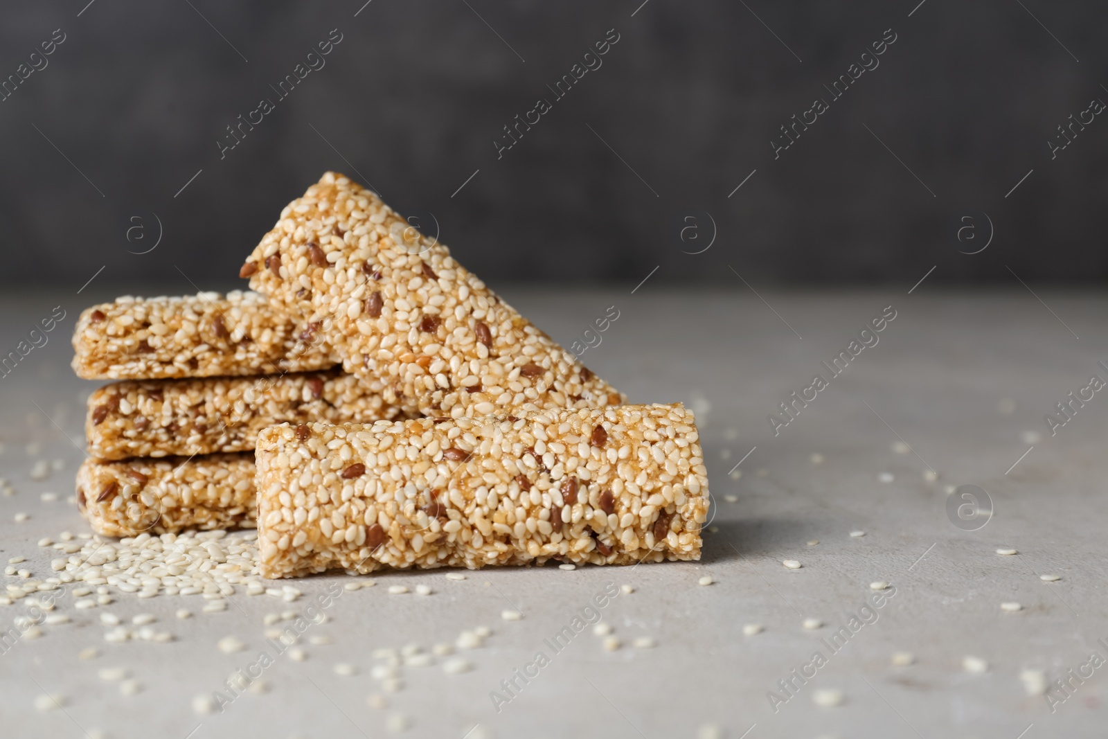 Photo of Tasty sesame seed bars on grey table. Space for text