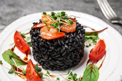 Delicious black risotto with seafood served on plate, closeup