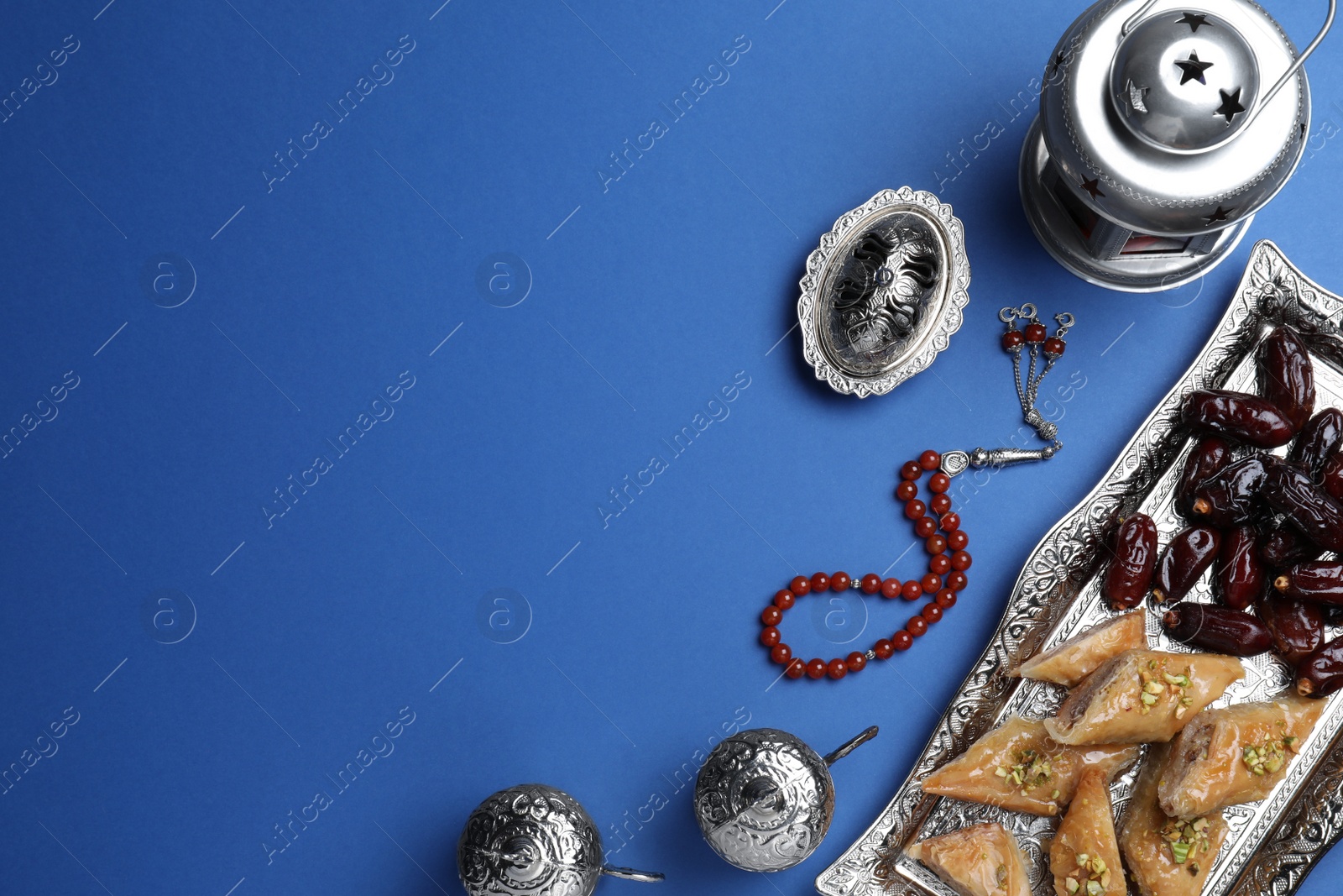 Photo of Flat lay composition with Arabic lantern and snacks on blue background. Space for text
