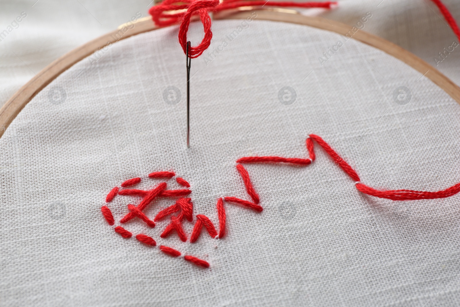 Photo of Sewing needle with thread and stitches on light cloth, closeup
