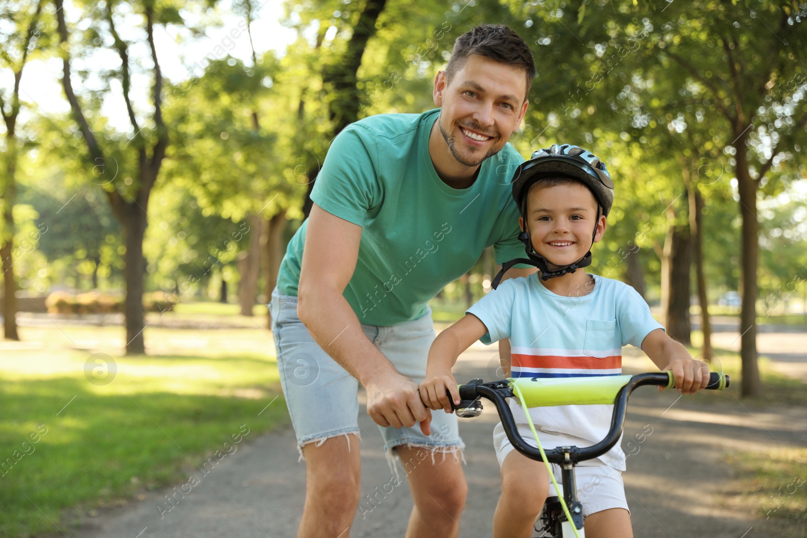Photo of Happy father teaching his son to ride bicycle in park
