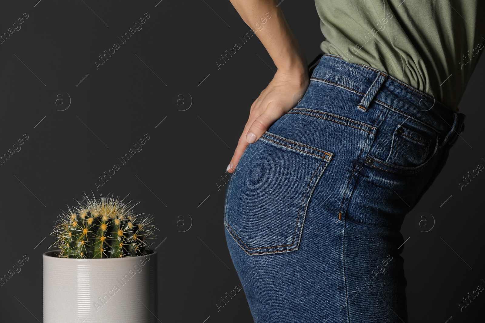 Photo of Woman sitting down on cactus against black background, closeup. Hemorrhoid concept