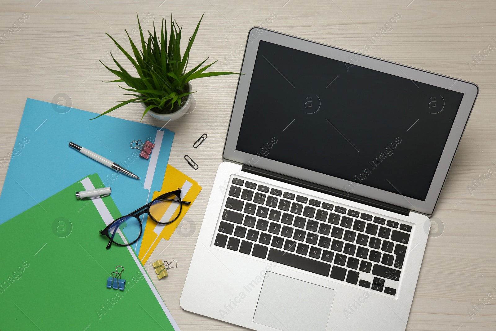 Photo of Modern laptop, glasses and office stationery on white wooden table, flat lay. Distance learning
