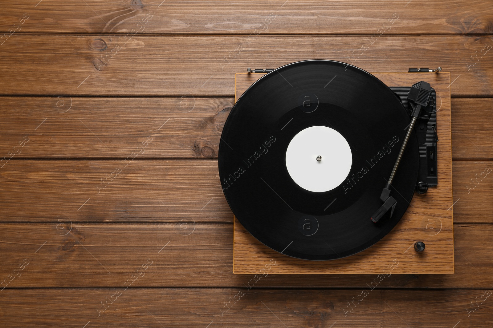 Photo of Turntable with vinyl record on wooden background, top view. Space for text