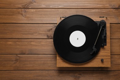 Turntable with vinyl record on wooden background, top view. Space for text