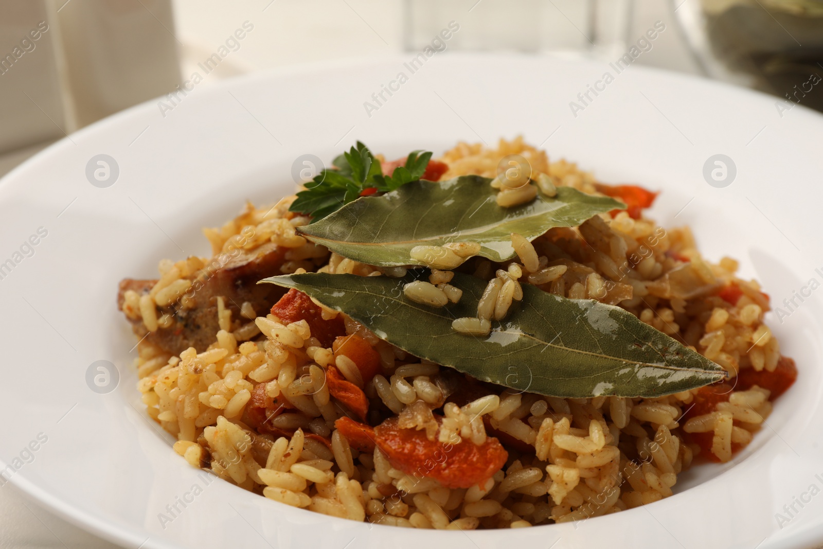 Photo of Delicious pilaf and bay leaves on plate, closeup