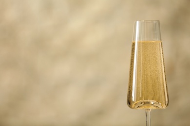 Glass of fizzy champagne against light background, space for text