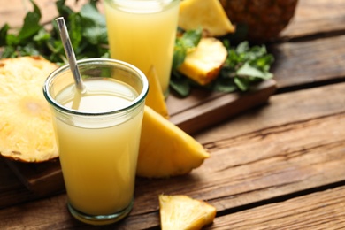 Photo of Delicious pineapple juice and fresh fruit on wooden table. Space for text