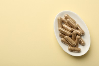 Vitamin capsules on pale yellow background, top view. Space for text