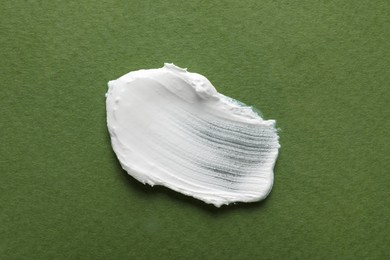 Photo of Smear of ointment on dark green background, top view