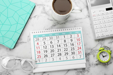 Flat lay composition with calendar and cup of coffee on white marble table