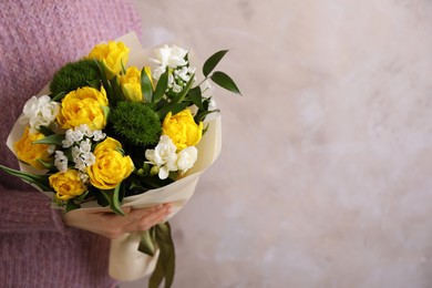 Woman with bouquet of beautiful tulips on beige background. Space for text