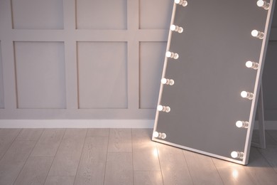 Modern mirror with light bulbs near molding wall in room, space for text