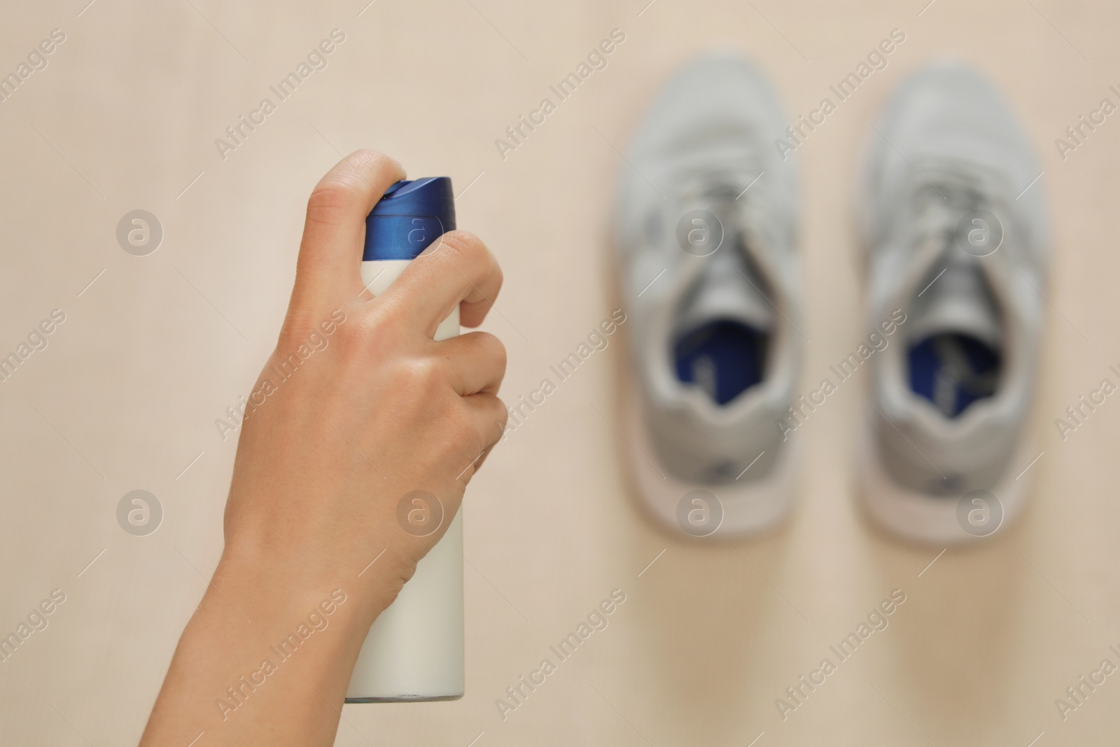 Photo of Woman spraying deodorant over pair of shoes at home, closeup. Space for text