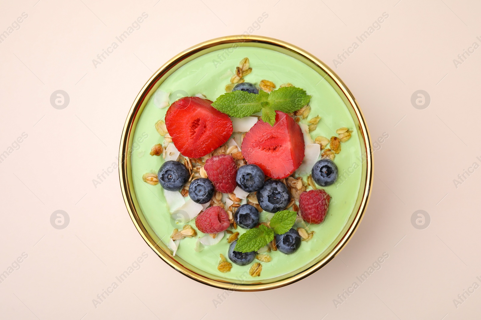Photo of Tasty matcha smoothie bowl served with berries and oatmeal on beige background, top view. Healthy breakfast