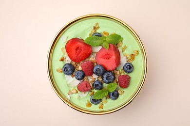 Tasty matcha smoothie bowl served with berries and oatmeal on beige background, top view. Healthy breakfast