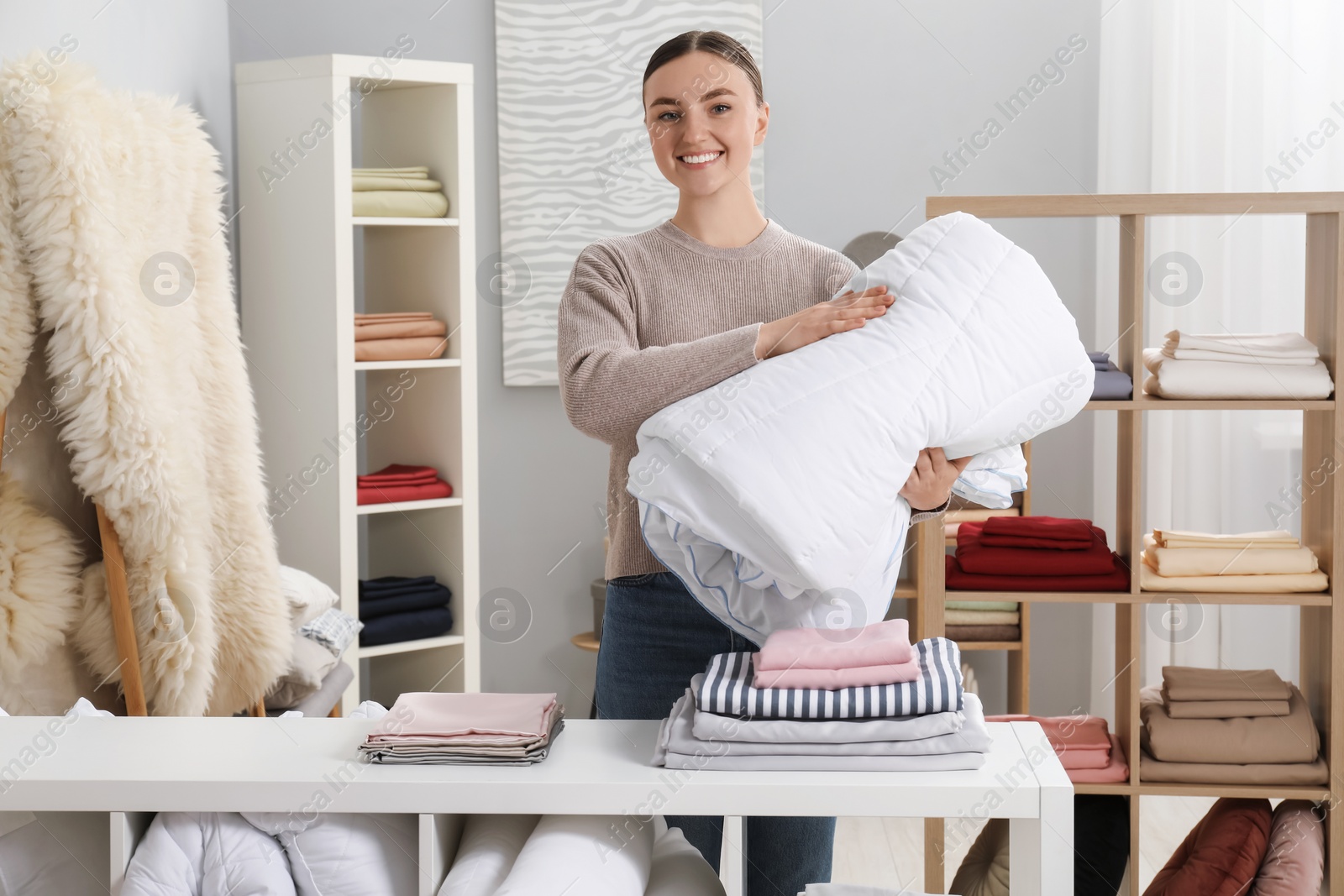 Photo of Smiling young woman with duvet in home textiles store