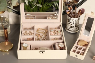 Photo of Elegant jewelry boxes with expensive wristwatches and beautiful bijouterie on grey table