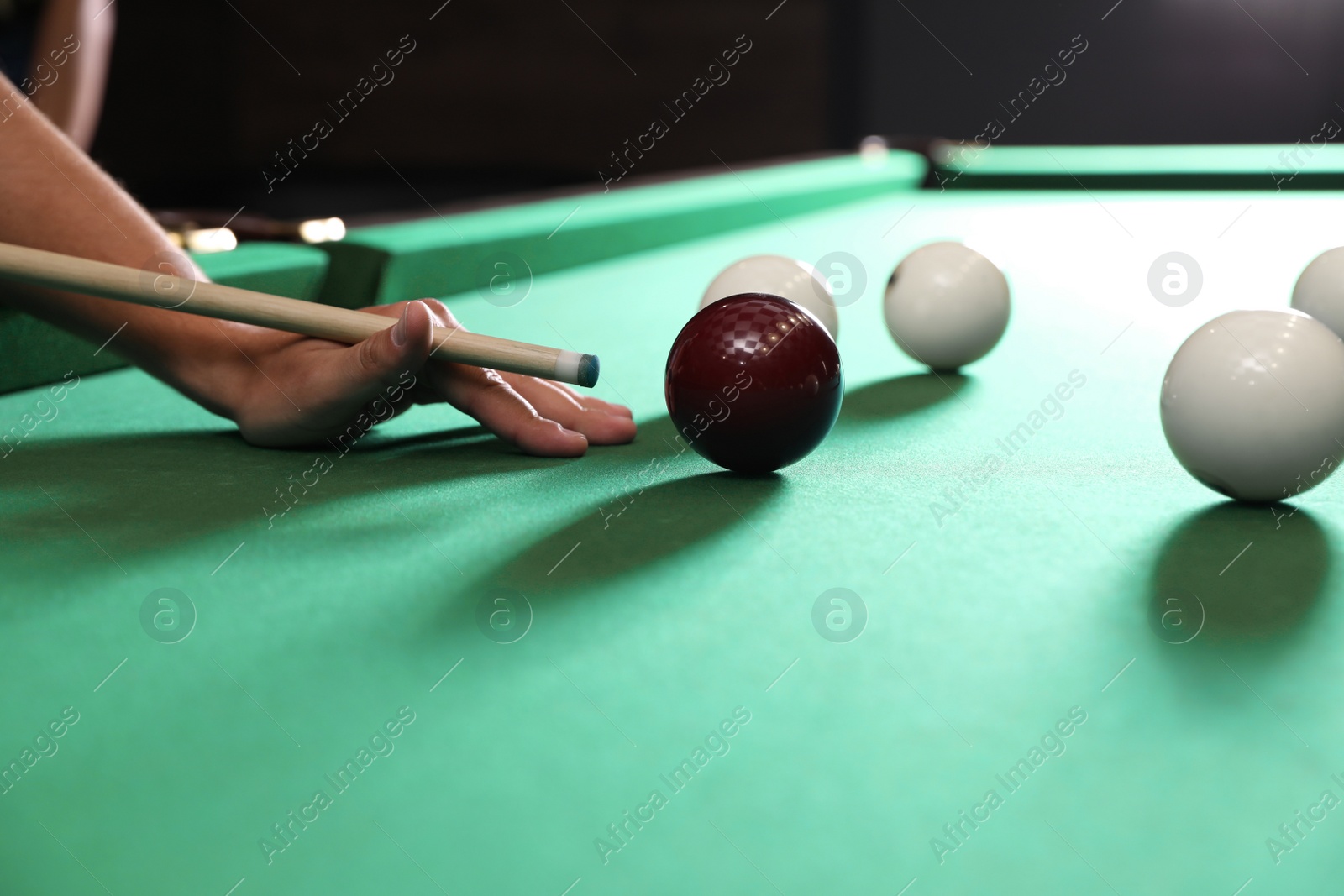 Photo of Young man playing Russian billiard indoors, closeup