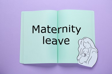 Photo of Maternity leave concept. Notebook with paper cutout of mother and child on violet background, top view
