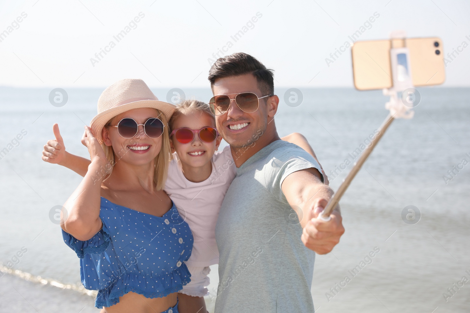 Photo of Happy family taking selfie at beach on sunny day