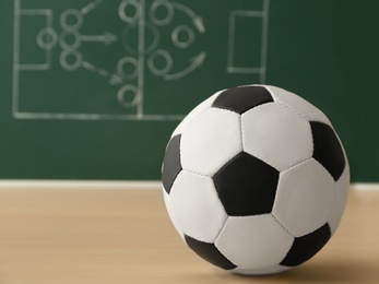 Soccer ball near chalkboard with football game scheme on table. Space for text