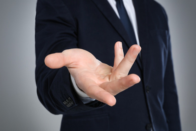 Photo of Businessman showing something against grey background, focus on hand