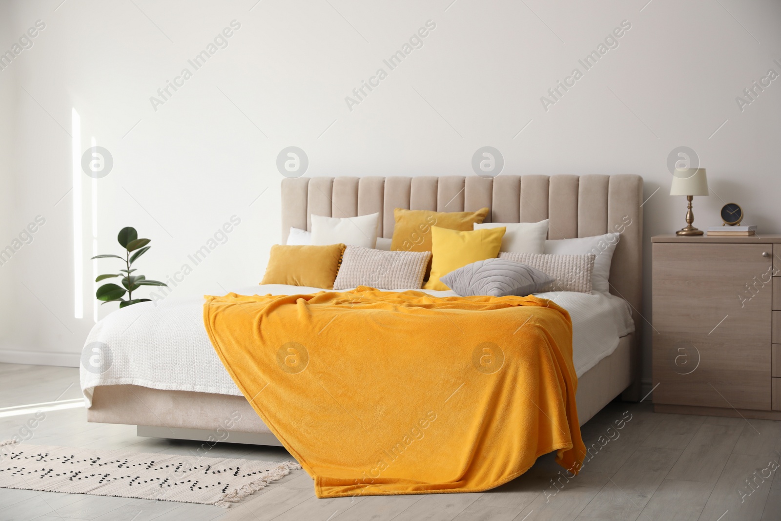 Photo of Stylish bedroom interior with soft yellow pillows and blanket