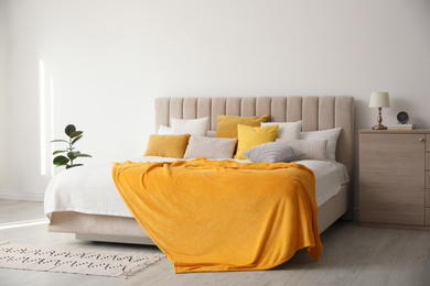 Photo of Stylish bedroom interior with soft yellow pillows and blanket